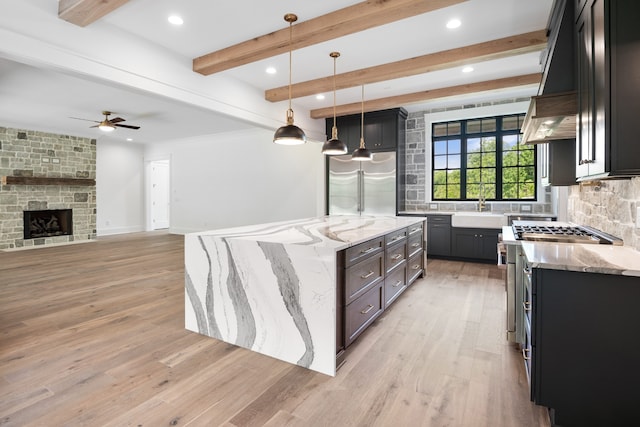 kitchen with light hardwood / wood-style floors, light stone countertops, a kitchen island, and high end appliances