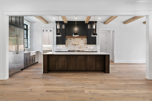 kitchen with decorative backsplash, appliances with stainless steel finishes, hanging light fixtures, and light hardwood / wood-style flooring