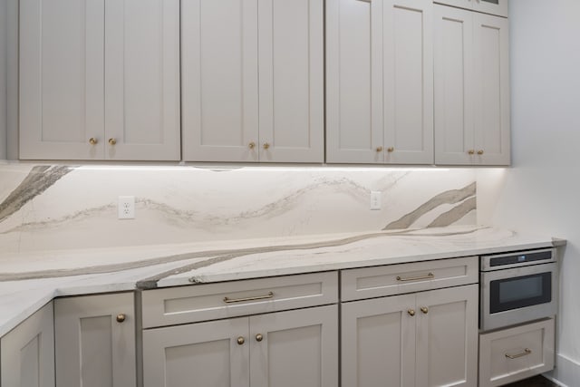 kitchen featuring light stone counters, oven, and gray cabinets