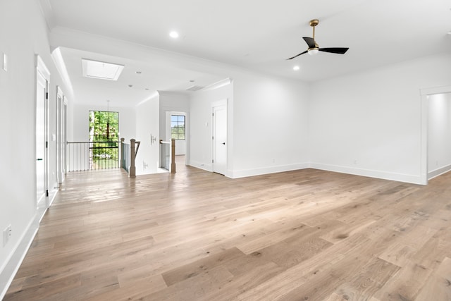 empty room featuring light hardwood / wood-style flooring, ceiling fan, a skylight, and crown molding