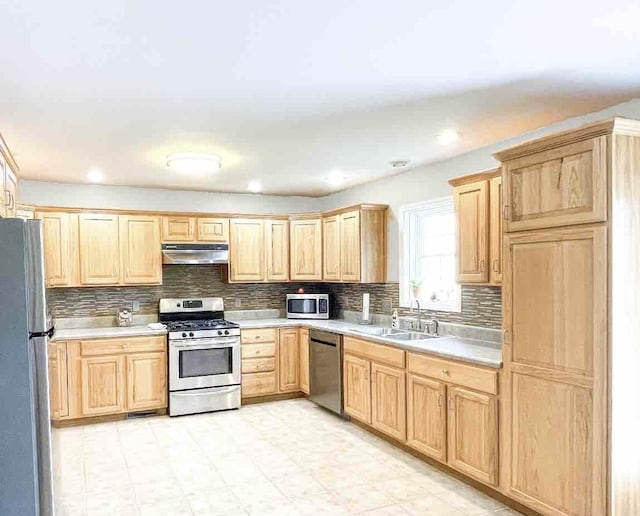 kitchen with appliances with stainless steel finishes, sink, light brown cabinets, and decorative backsplash