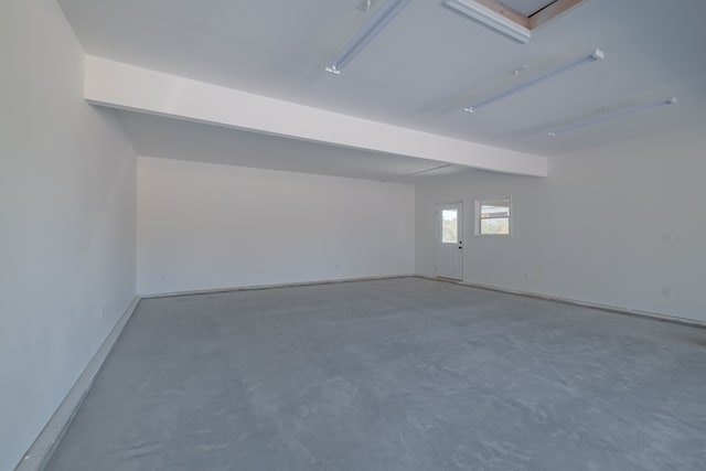 empty room with concrete floors and beamed ceiling