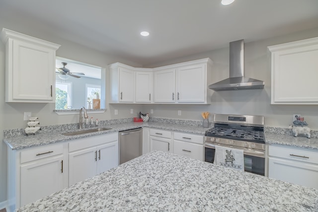 kitchen with sink, white cabinets, wall chimney range hood, and appliances with stainless steel finishes