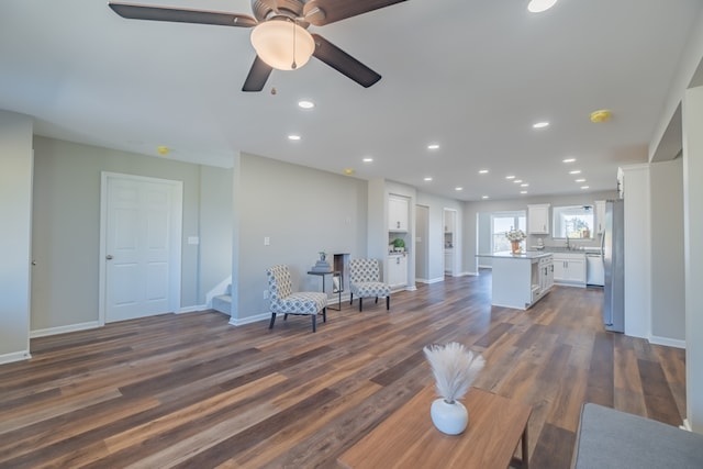 unfurnished living room with ceiling fan, dark hardwood / wood-style flooring, and sink