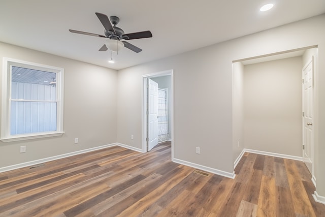 empty room with ceiling fan and dark hardwood / wood-style flooring