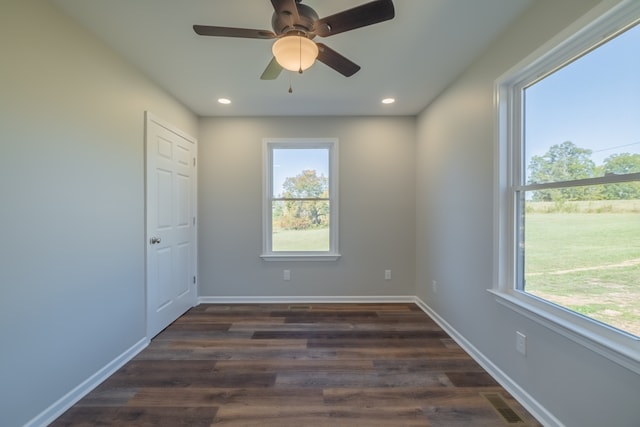 spare room with dark wood-type flooring, ceiling fan, and a wealth of natural light