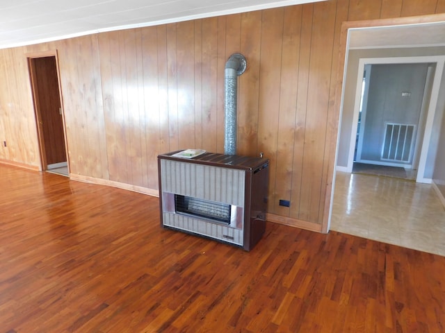 unfurnished living room featuring wood walls, dark hardwood / wood-style floors, and heating unit