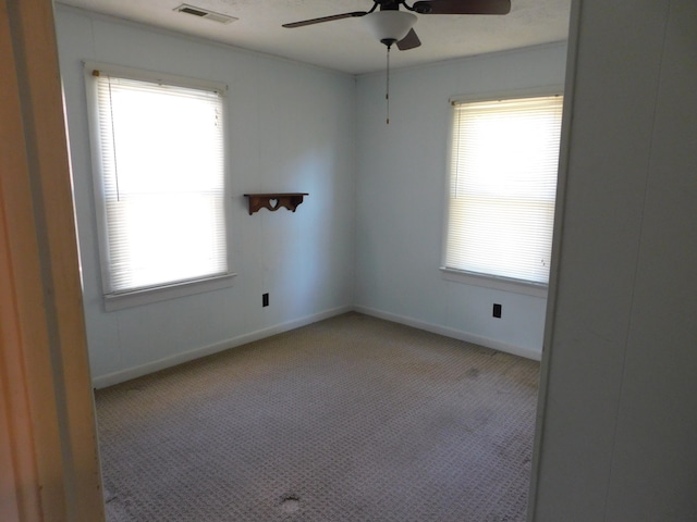 spare room featuring ceiling fan, a wealth of natural light, and light colored carpet