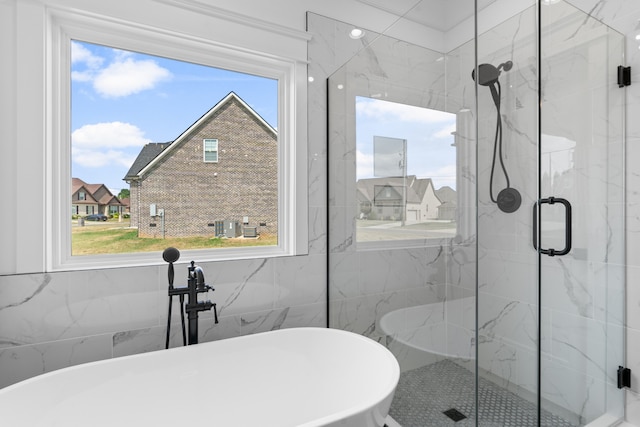 bathroom with tile walls, a healthy amount of sunlight, and separate shower and tub