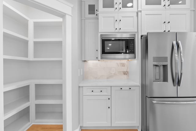 kitchen with appliances with stainless steel finishes, decorative backsplash, and white cabinets