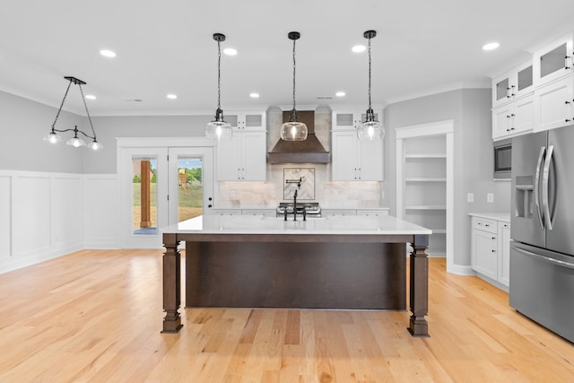 kitchen featuring a center island with sink, white cabinetry, light hardwood / wood-style flooring, custom range hood, and stainless steel appliances