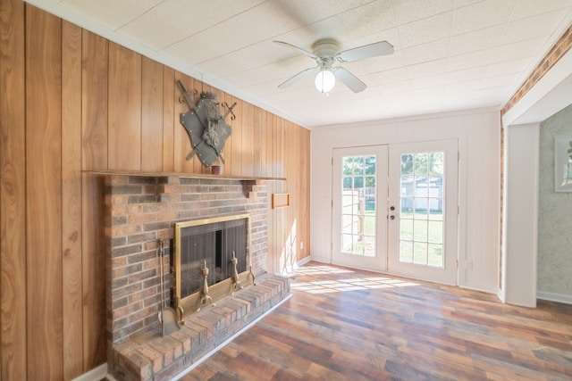 unfurnished living room with french doors, hardwood / wood-style floors, wood walls, and a fireplace