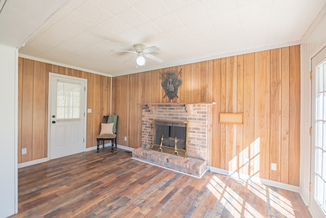 unfurnished living room with wooden walls, ornamental molding, dark hardwood / wood-style flooring, and a brick fireplace