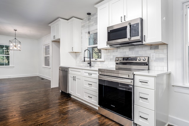 kitchen with sink, stainless steel appliances, decorative light fixtures, white cabinets, and dark wood-type flooring