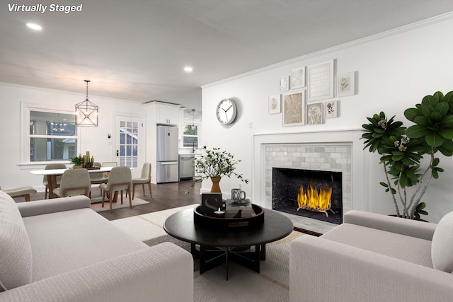 living room with ornamental molding, sink, dark wood-type flooring, and a brick fireplace