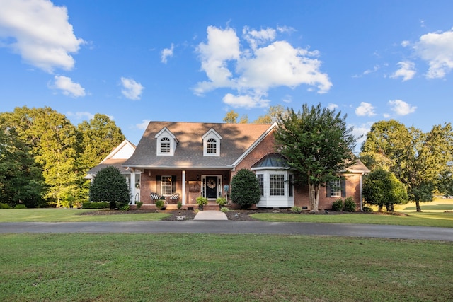 new england style home featuring a front yard and a porch