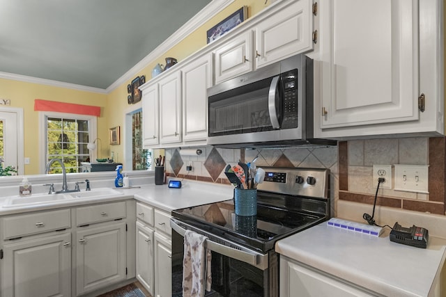 kitchen with decorative backsplash, ornamental molding, sink, white cabinetry, and appliances with stainless steel finishes