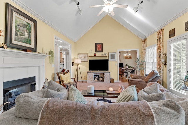 living room with a tiled fireplace, lofted ceiling, track lighting, and ornamental molding