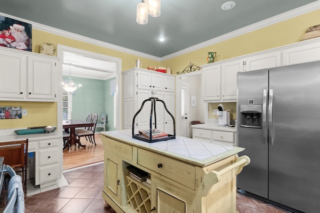 kitchen featuring hanging light fixtures, tile counters, white cabinets, crown molding, and stainless steel refrigerator with ice dispenser