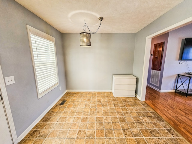 unfurnished dining area with light hardwood / wood-style flooring and a textured ceiling