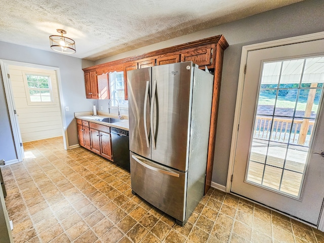 kitchen featuring a textured ceiling, dishwasher, sink, and stainless steel fridge