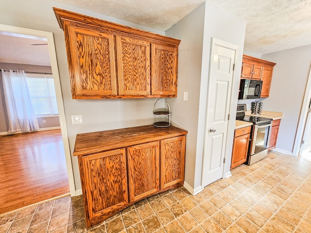 kitchen with light hardwood / wood-style flooring, a textured ceiling, and stainless steel range with electric cooktop