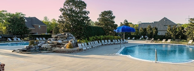 pool at dusk featuring a patio area