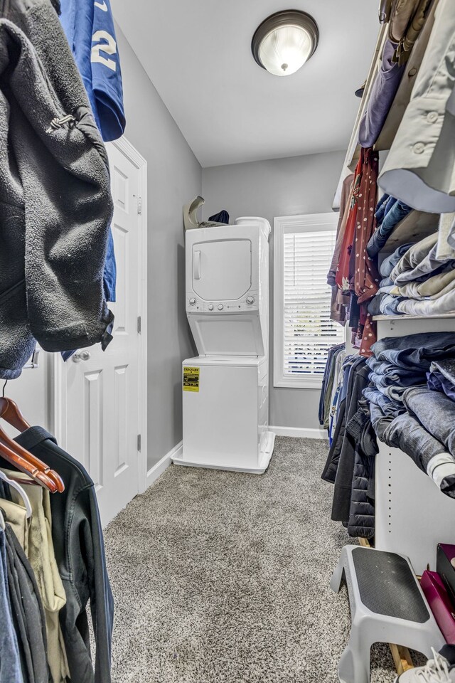 spacious closet featuring stacked washer / drying machine and carpet floors