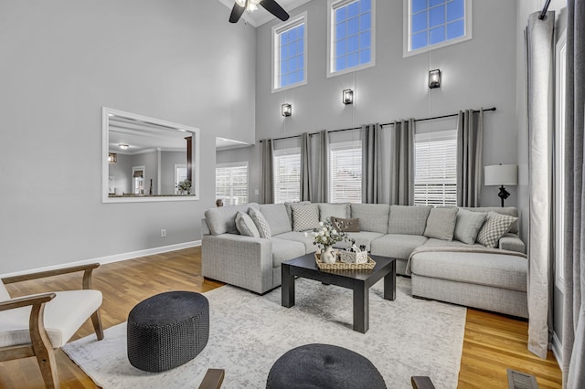 living room featuring light hardwood / wood-style floors, a high ceiling, and ceiling fan