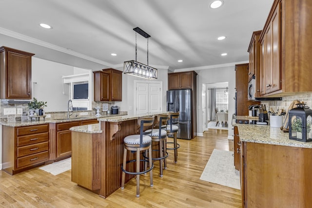 kitchen featuring light hardwood / wood-style flooring, stainless steel appliances, sink, pendant lighting, and a center island