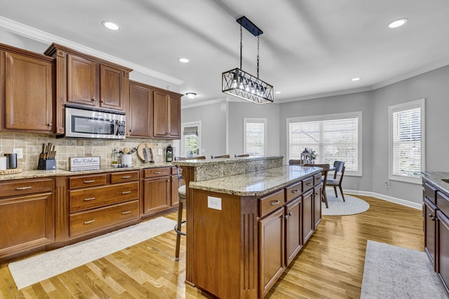 kitchen with a breakfast bar, a center island, hanging light fixtures, and light wood-type flooring