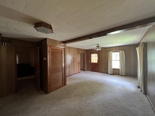 carpeted empty room featuring wood walls and ceiling fan