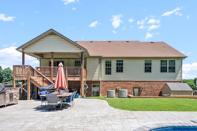 back of property featuring a lawn, a wooden deck, a patio, and central AC unit