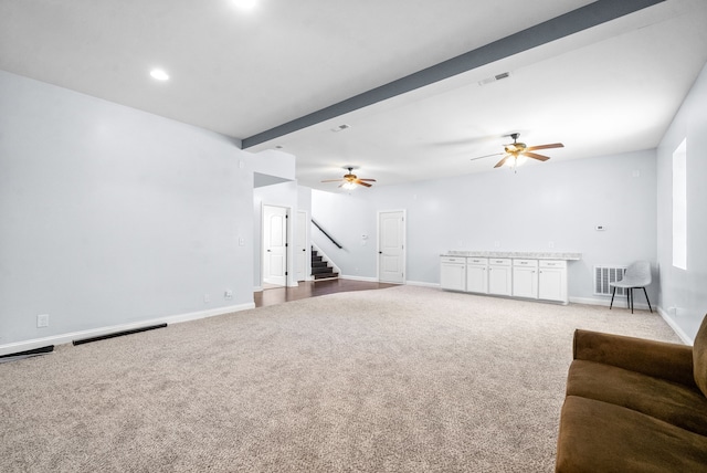 unfurnished living room with ceiling fan, carpet, and beamed ceiling