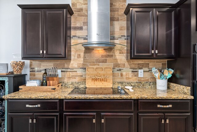 kitchen featuring black electric stovetop, backsplash, dark brown cabinets, light stone counters, and extractor fan