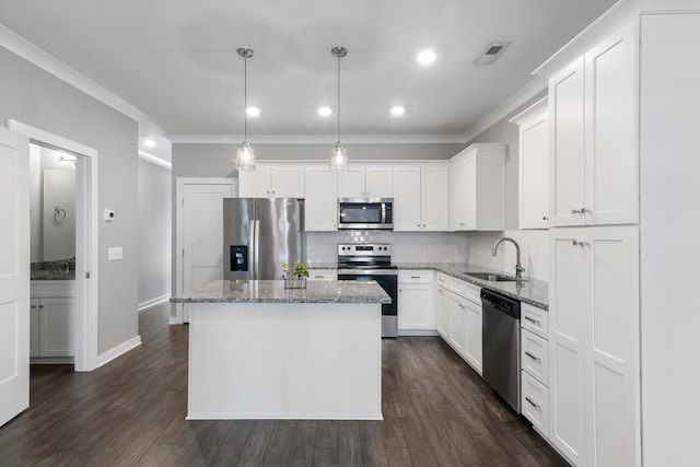 kitchen featuring appliances with stainless steel finishes, sink, a center island, decorative light fixtures, and dark wood-type flooring