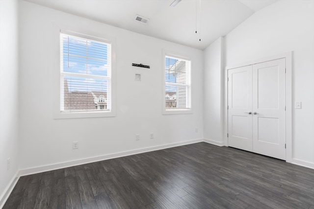 unfurnished bedroom with dark wood-type flooring, vaulted ceiling, multiple windows, and a closet