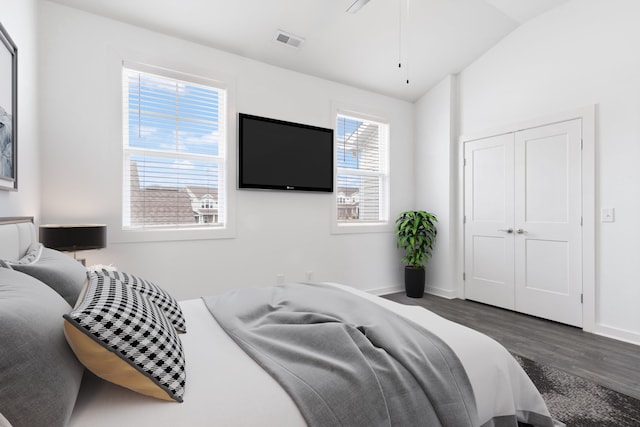 bedroom with dark wood-type flooring, vaulted ceiling, and a closet