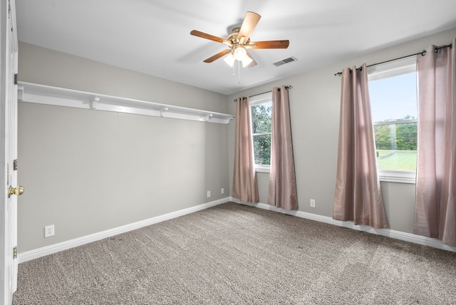 carpeted spare room featuring ceiling fan and a wealth of natural light