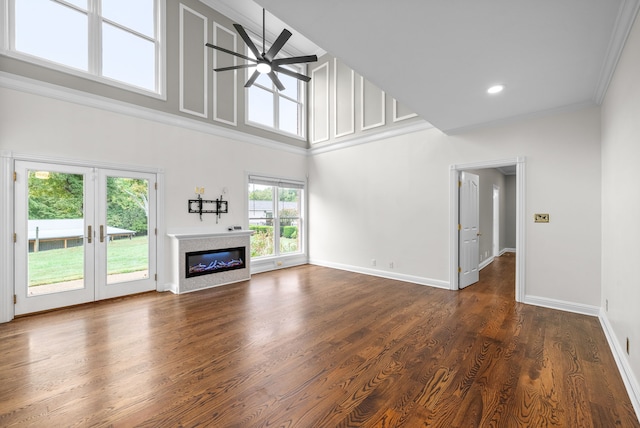 unfurnished living room with ceiling fan, dark wood-type flooring, a high ceiling, crown molding, and french doors