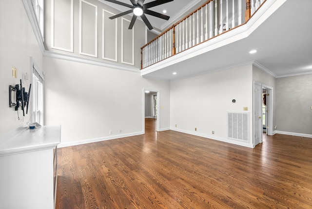 unfurnished living room with crown molding, dark hardwood / wood-style floors, a high ceiling, and ceiling fan