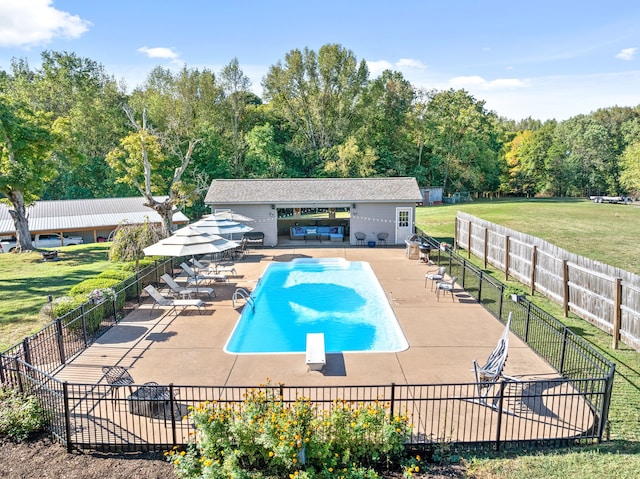 view of pool with a patio, a diving board, and a yard