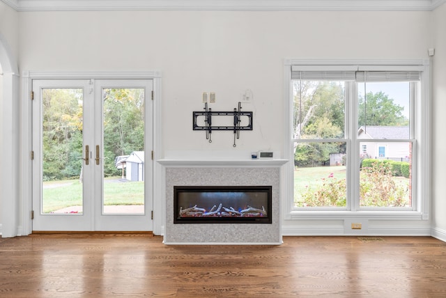 unfurnished living room featuring french doors, crown molding, hardwood / wood-style flooring, and plenty of natural light