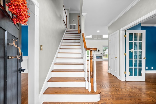 stairs with ornamental molding and hardwood / wood-style flooring