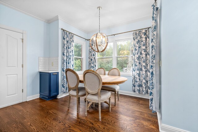 dining space featuring dark wood-type flooring, ornamental molding, and an inviting chandelier