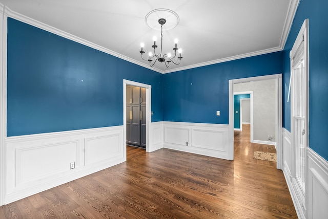 spare room with crown molding, dark hardwood / wood-style flooring, and a chandelier