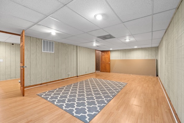 basement with a paneled ceiling, hardwood / wood-style flooring, and wooden walls