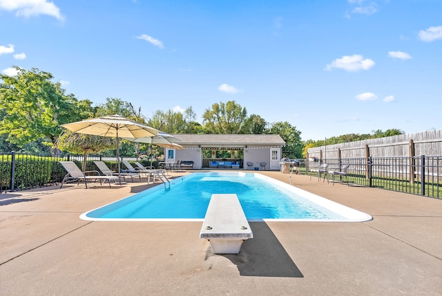 view of pool with a patio area and a diving board