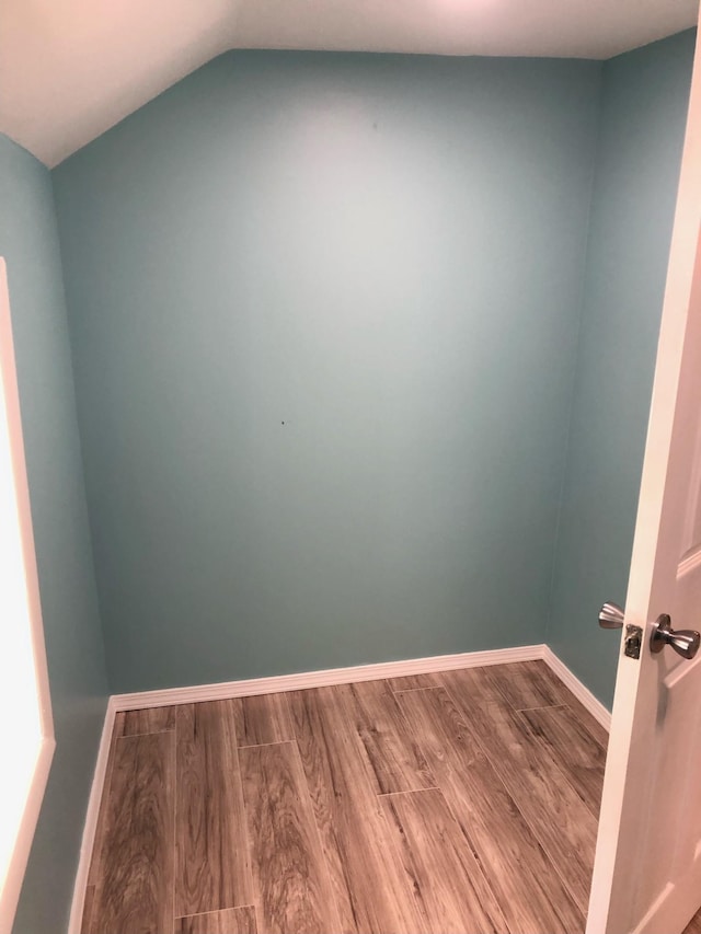 empty room with baseboards, wood finished floors, and lofted ceiling