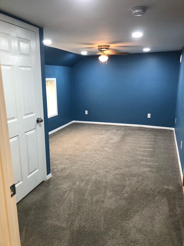 carpeted spare room featuring a ceiling fan, baseboards, and lofted ceiling